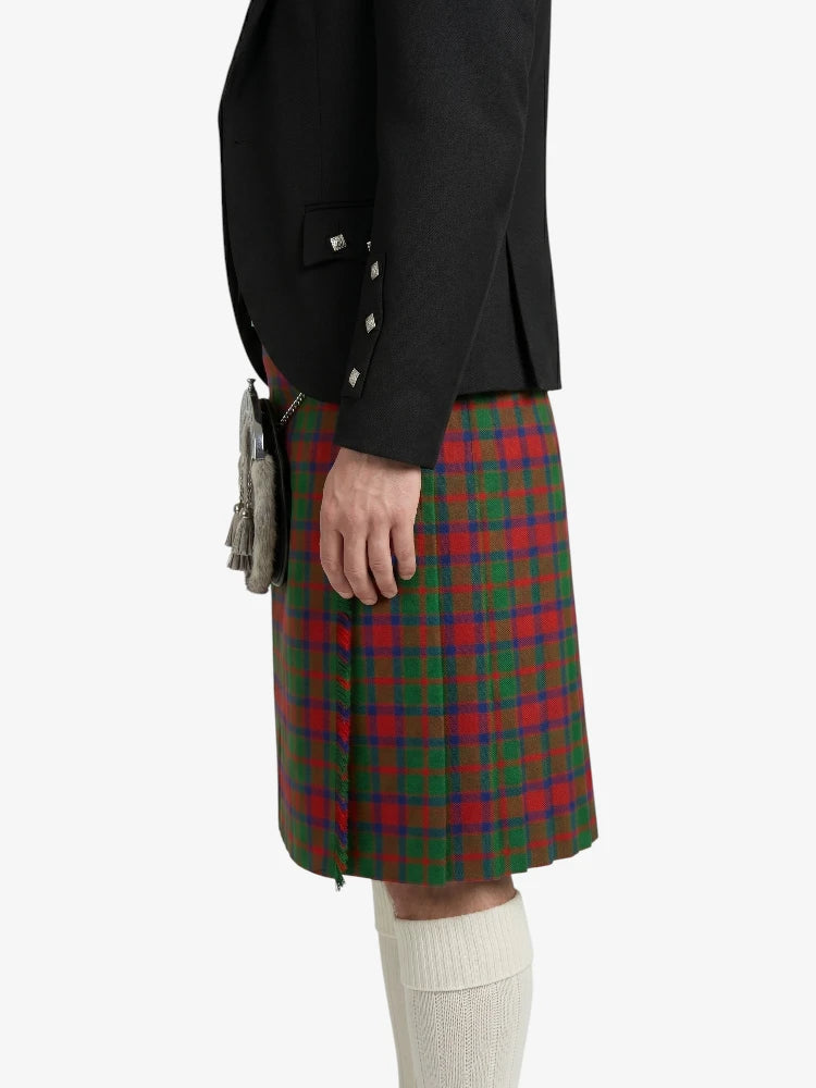 Person wearing a black jacket and red, green, and blue plaid kilt on a white background