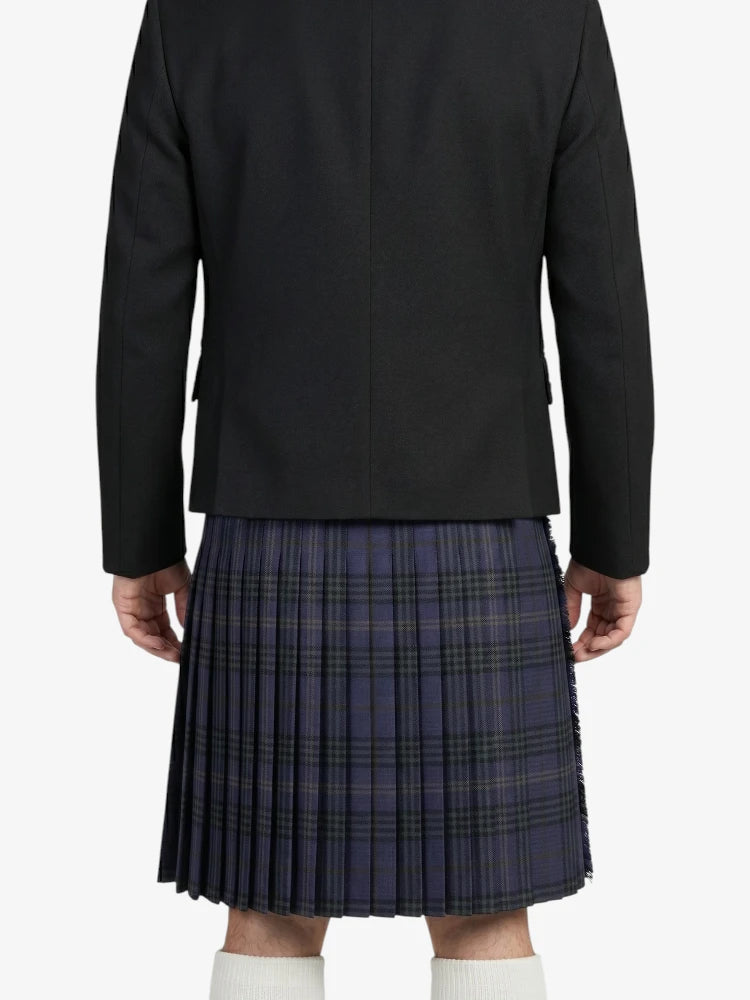 Person wearing a black blazer and plaid kilt on a white background