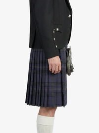 Person wearing a dark blazer and plaid kilt on a white background
