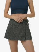 Person wearing a black crop top and gray skirt on a white background