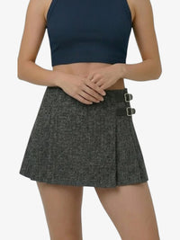 Person wearing a black crop top and gray skirt on a white background