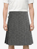 Person wearing a white shirt and black and white patterned skirt on a plain background