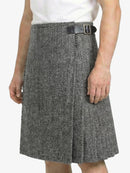 Person wearing a gray herringbone skirt with a black belt on a white background
