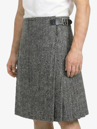 Person wearing a gray herringbone skirt with a black belt on a white background