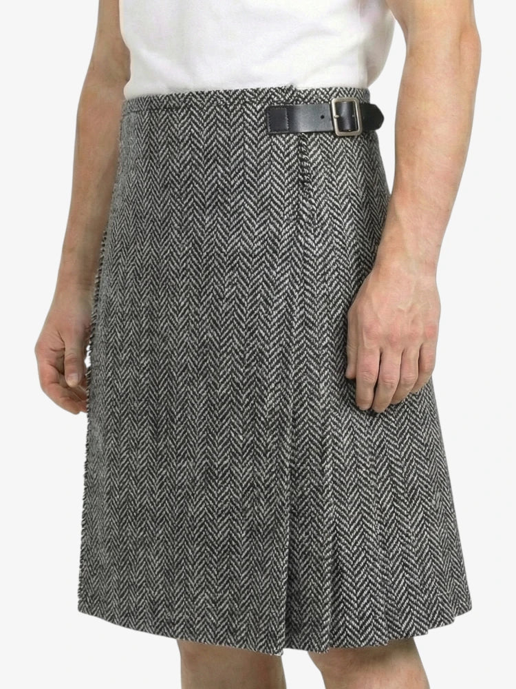 Person wearing a gray herringbone skirt with a black belt on a white background