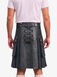 A person shown from the back wearing a black pleated leather kilt with front lace-up detailing and side pockets, paired with a light pink t-shirt and white socks, against a plain light background.
