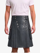 A person wearing a dark gray faux-leather kilt with silver-tone metal rivets and flap pockets, paired with a light pink t-shirt, shown against a plain white background.