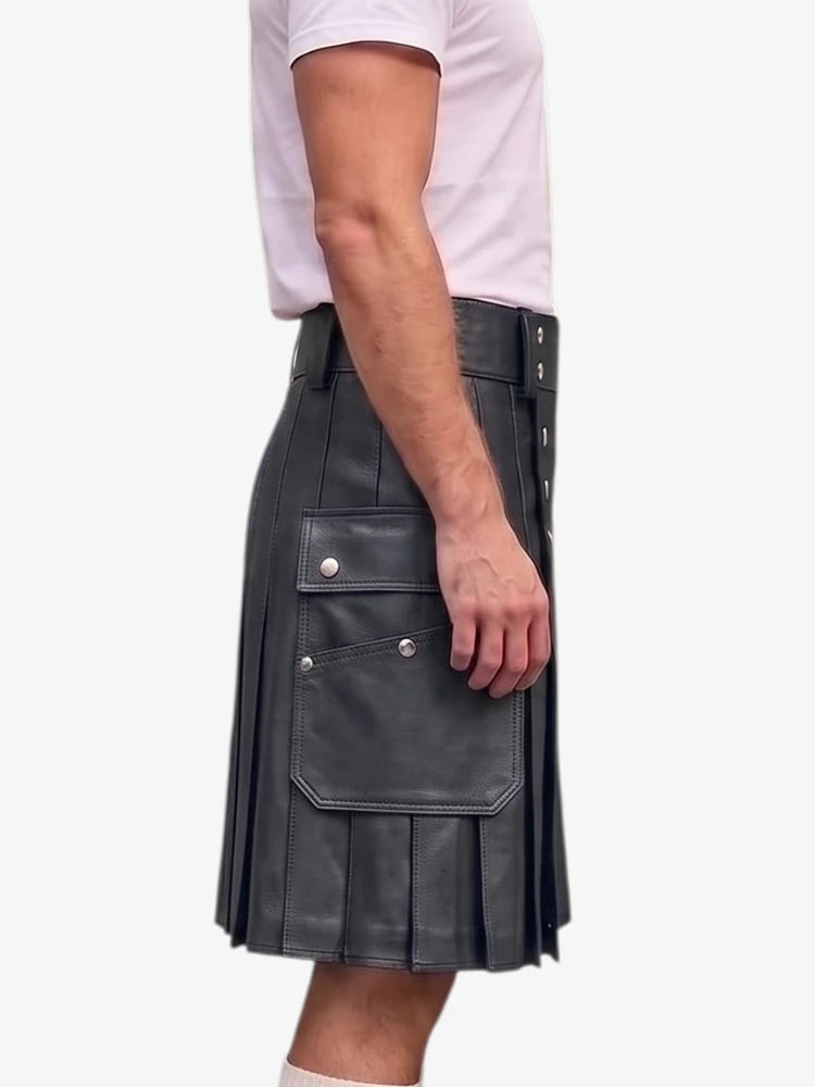 A side view of a person wearing a dark gray faux-leather kilt with pleats, a front flap pocket with silver snaps, and a matching belt, paired with a light pink t-shirt against a plain white background.