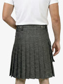 Person wearing a gray pleated kilt on a white background