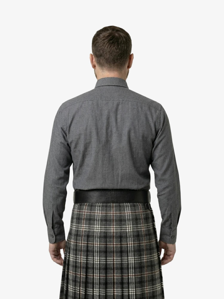Man wearing a gray shirt and plaid kilt on a white background