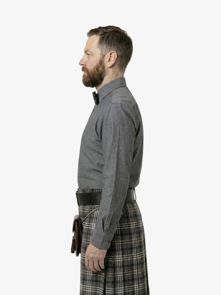Man wearing a gray shirt and plaid kilt on a white background