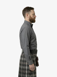 Man wearing a gray shirt and plaid kilt on a white background