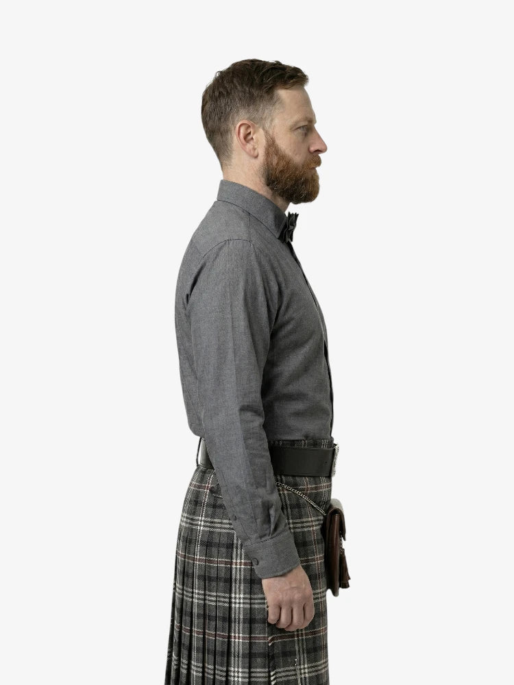 Man wearing a gray shirt and plaid kilt on a white background
