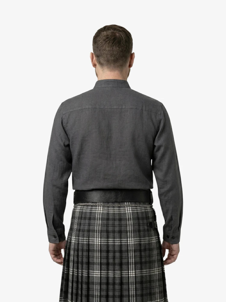 Man wearing a dark shirt and plaid kilt on a white background