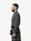 Man wearing a gray shirt and plaid kilt on a white background