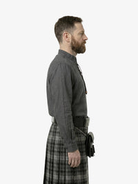 Man wearing a gray shirt and plaid kilt on a white background