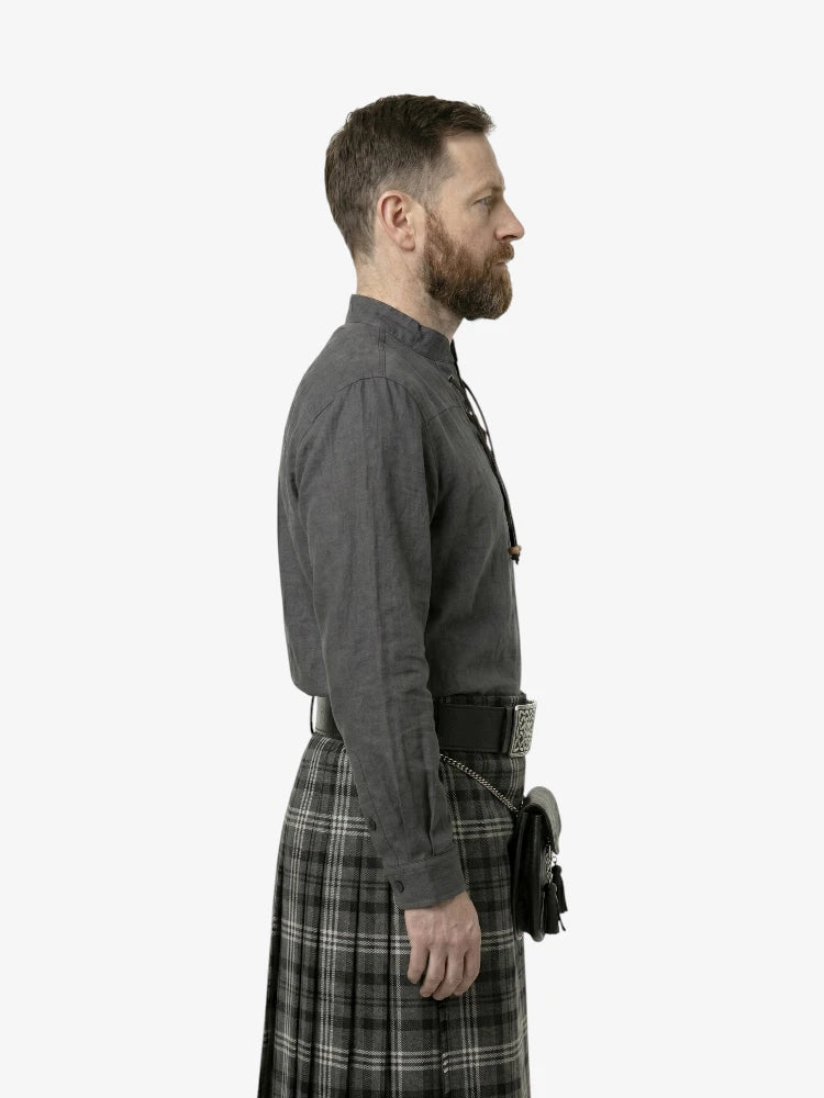Man wearing a gray shirt and plaid kilt on a white background