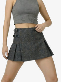 Person wearing a gray pleated skirt and crop top on a white background