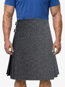 Person wearing a gray patterned kilt over a blue shirt on a white background