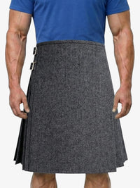 Person wearing a gray patterned kilt over a blue shirt on a white background