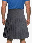 Person wearing a gray pleated kilt on a white background