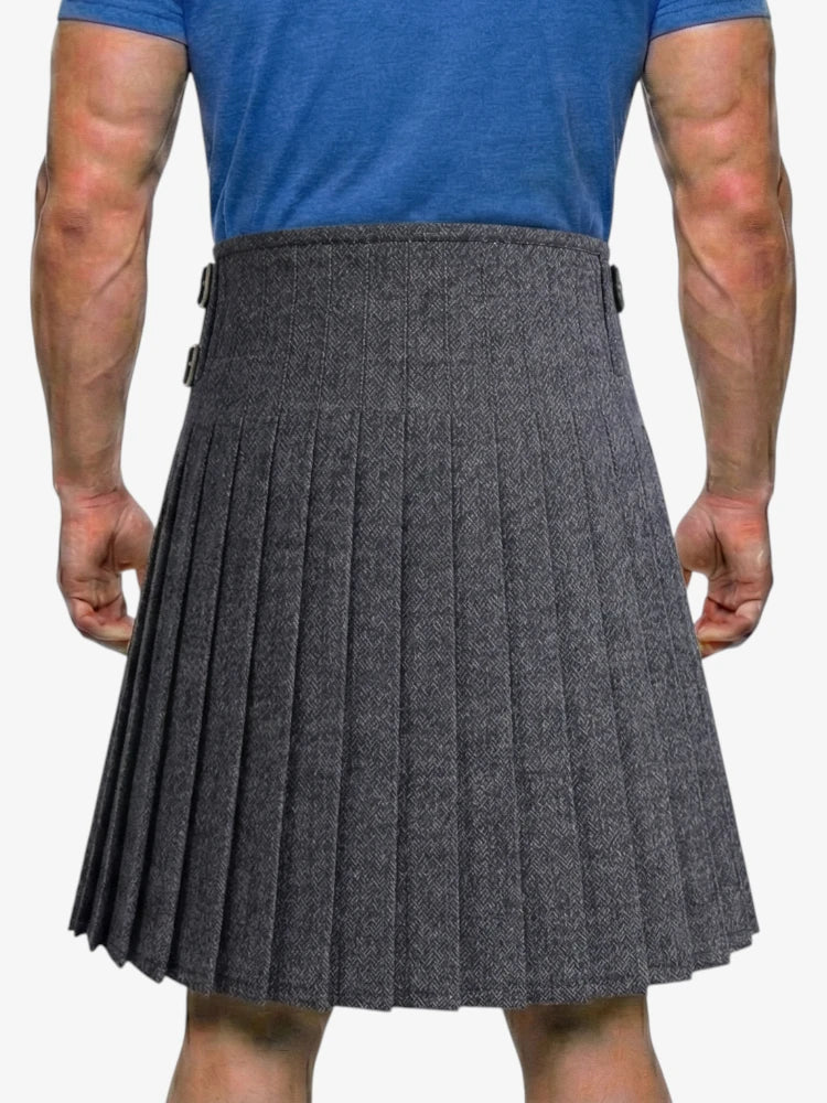 Person wearing a gray pleated kilt on a white background