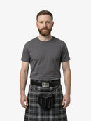 Man wearing a gray t-shirt and plaid kilt on a white background