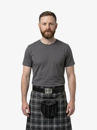 Man wearing a gray t-shirt and plaid kilt on a white background