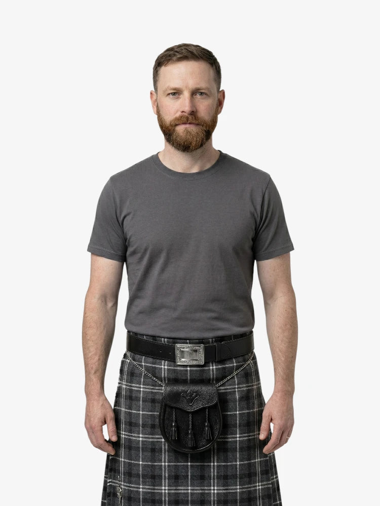 Man wearing a gray t-shirt and plaid kilt on a white background