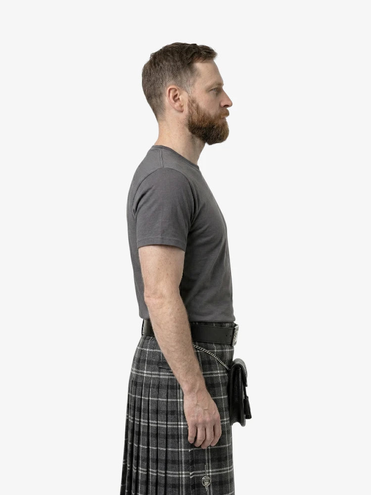 Man wearing a gray t-shirt and plaid kilt on a white background