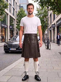A man stands on a city sidewalk wearing a black leather kilt with gold buttons, a white t-shirt, white knee-high socks, and black leather shoes. The background shows a street with buildings, a parked black Mercedes, and a bicycle.
