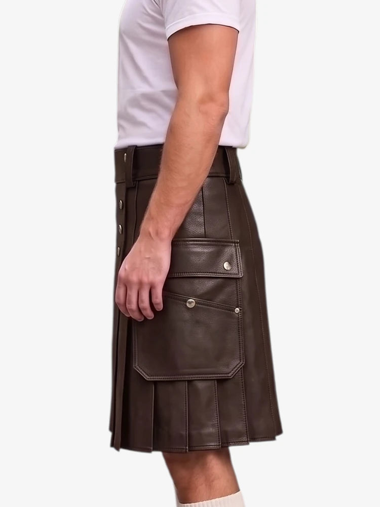 A man wearing a dark brown faux-leather kilt with pleated detailing and front cargo pockets, paired with a white t-shirt, shown from a side profile against a light gray background.