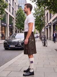 A man standing on a city sidewalk wearing a dark brown leather kilt, a white t-shirt, white socks with purple accents, and black leather shoes. A black Mercedes-Benz car is parked on the street behind him.