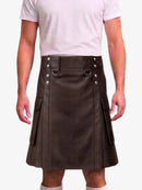 A man wearing a dark brown faux-leather kilt with silver-tone metal hardware and side pockets, paired with a light pink t-shirt and white socks, shown from the chest down against a white background.