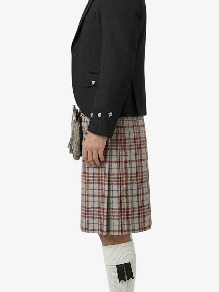 Person wearing a black jacket and plaid kilt on a white background