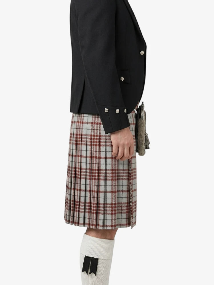 Person wearing a black blazer and plaid kilt on a white background