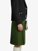 Person wearing a black blazer and green plaid kilt on a white background