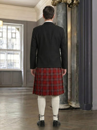 Person wearing a black jacket and red plaid kilt in an elegant room.