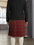 Person wearing a black jacket and red plaid kilt indoors.