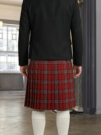 Person wearing a black jacket and red plaid kilt indoors.