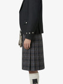 Person wearing a black jacket and plaid kilt on a white background