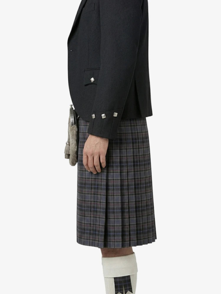 Person wearing a black jacket and plaid kilt on a white background