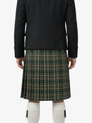Person wearing a black jacket and green plaid skirt on a white background