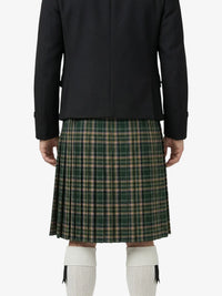Person wearing a black jacket and green plaid skirt on a white background