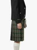 Person wearing a black jacket and green plaid kilt on a white background