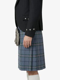 Person wearing a black jacket and blue plaid kilt on a white background