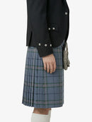 Person wearing a dark jacket and blue plaid kilt on a white background