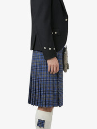 Person wearing a dark jacket and blue plaid kilt on a white background