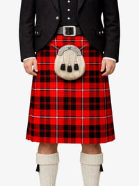 Person wearing a red tartan kilt with a black jacket and white socks on a white background