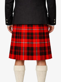 Red plaid kilt worn with a black jacket and white knee-high socks on a white background